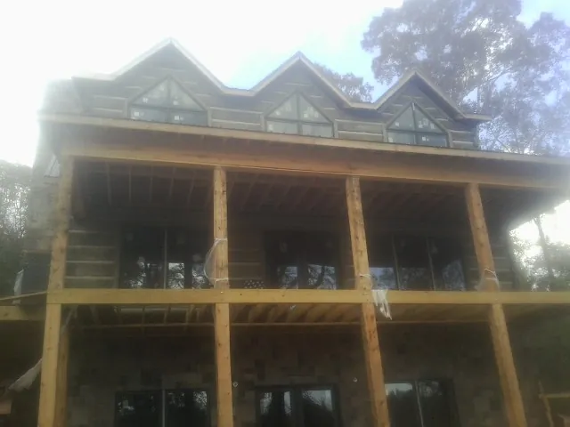 Dormers and porch framing on a large log home under construction — Roof Coating work by our crew in Bethany